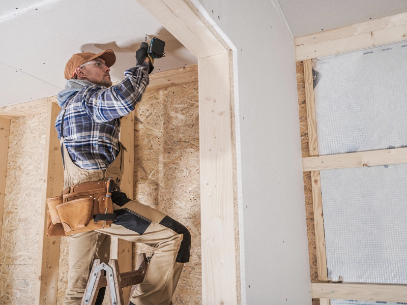 A worker doing construction work on a drywall